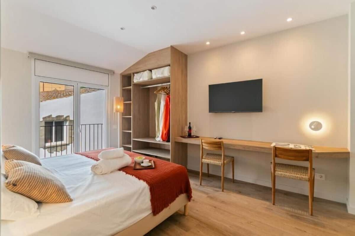 A bedroom with a bed, a desk, and a TV.