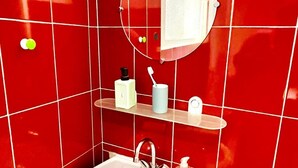 A bathroom with red tiles, a white sink, a mirror, and a towel rack. - Le SAINT CLEMENT in the heart of Nantes 5min from Nantes Nord train station (Nantes)