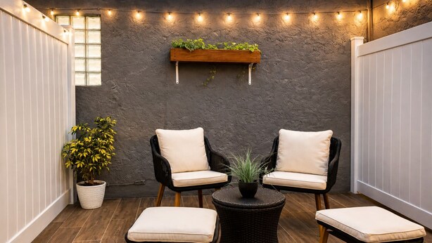 A patio area with two black wicker chairs, a small round table with a plant, and a potted plant. - E&A SouthWest Miami Rentals Cozy 2BD Apartment with Private Parking (miami)