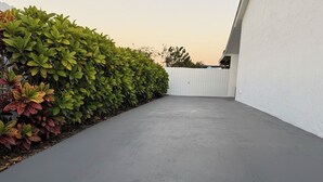 A paved pathway leading to a white fence, bordered by green foliage. - E&A SouthWest Miami Rentals Cozy 2BD Apartment with Private Parking (miami)