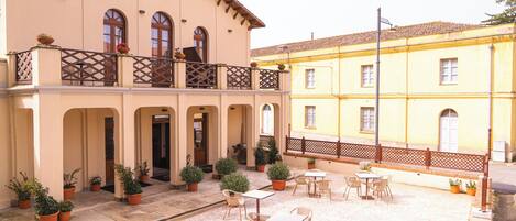 A building with a balcony, outdoor seating area, and potted plants.