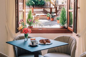 Una mesa con una taza, un plato con croissants y un jarrón de flores.