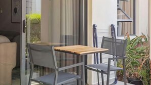 A modern outdoor patio with a sliding glass door leading to a living area, a wooden table with two chairs, and a potted plant. - The Henlee Apartment Dainfern (Dainfern)