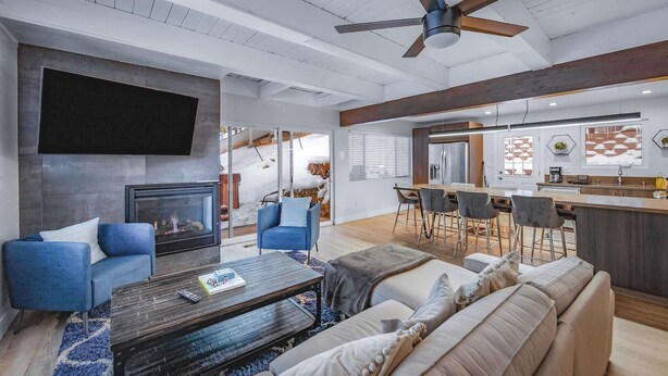 A spacious living room with a fireplace, a large TV, and a ceiling fan. - Zephyr Chalet Home for 8 (Zephyr Cove)