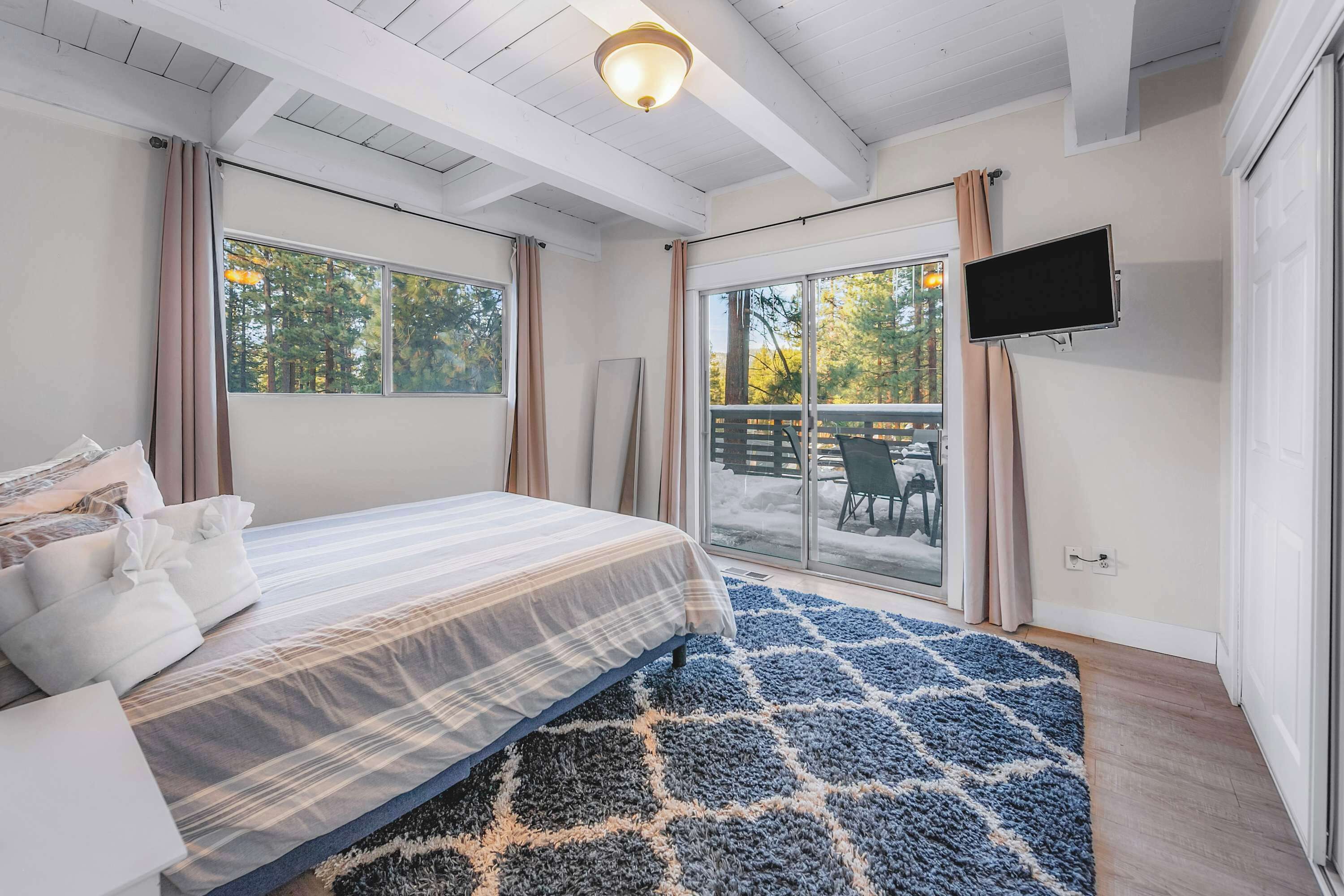 A bedroom with a bed, a TV, and a view of the outdoors.