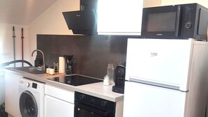 Eine kompakte Küche mit Waschmaschine, Backofen, Mikrowelle und Kaffeemaschine.