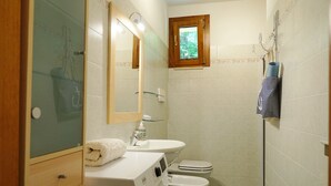 Ein kleines Badezimmer mit Waschmaschine, Waschbecken, Toilette und einem kleinen Fenster.