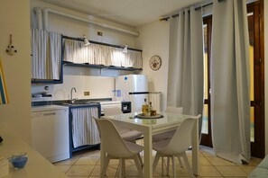 A compact kitchen with a dishwasher, a refrigerator, and a dining table with chairs. - Romantic Escape Nestled in the Hills (Villanuova sul Clisi)