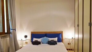 Ein ordentlich bezogenes Bett mit blau-weißer Bettwäsche, ein Weiden-Kopfseitenverkleidung und ein Nachttisch mit einer Lampe.