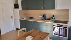 Ett kompakt kök med ett träbord, en diskho, en kaffebryggare och en inbyggd ugn.
