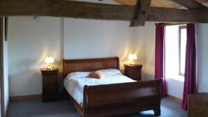 Un dormitorio con una cama de madera, dos lámparas de noche, un ventanal con cortinas y techo de madera.