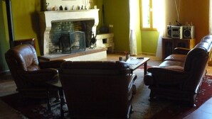 Una sala de estar con chimenea, sofás de cuero y un televisor.