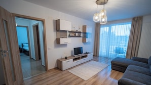 Ein modernes Wohnzimmer mit Holzboden, einer Couch, einem Fernseher und einer integrierten Unterhaltungseinheit.