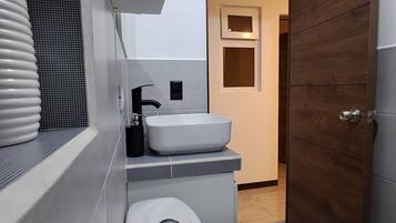 Un baño moderno con inodoro, lavabo y cabina de ducha.