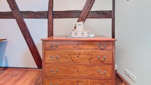 A wooden dresser with drawers and a decorative top, placed in a room with exposed wooden beams on the ceiling. - La Perle du Ried n°6 - Alsatian charm and tranquillity just a stone's throw from Europa-Park (Boofzheim)