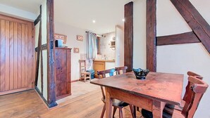 A rustic dining area with a wooden table and chairs, a wooden cabinet, and exposed beams. - La Perle du Ried n°6 - Alsatian charm and tranquillity just a stone's throw from Europa-Park (Boofzheim)