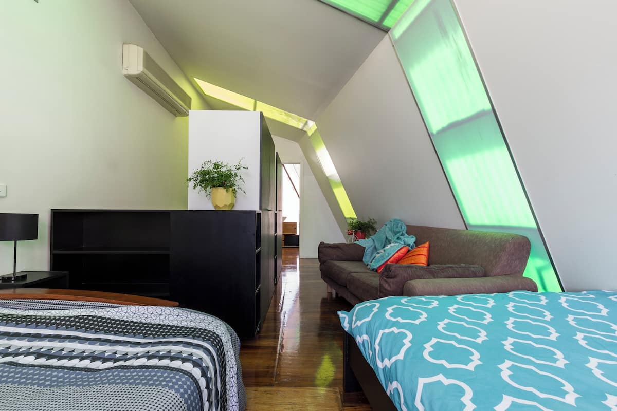 A modern bedroom with a bed, a sofa, a TV, and a plant.