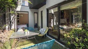 A modern patio with a glass door, a table, and chairs. - Melb suite zen garden A0 F1 (West Melbourne)