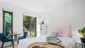 A bedroom with a large bed, a small table, two chairs, and a potted plant. - Melb suite zen garden A0 F1 (West Melbourne)
