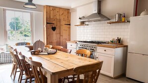 A modern kitchen with a wooden dining table, white cabinets, and a gas stove.
