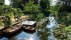A calm river with boats docked on the left, surrounded by lush greenery and trees.