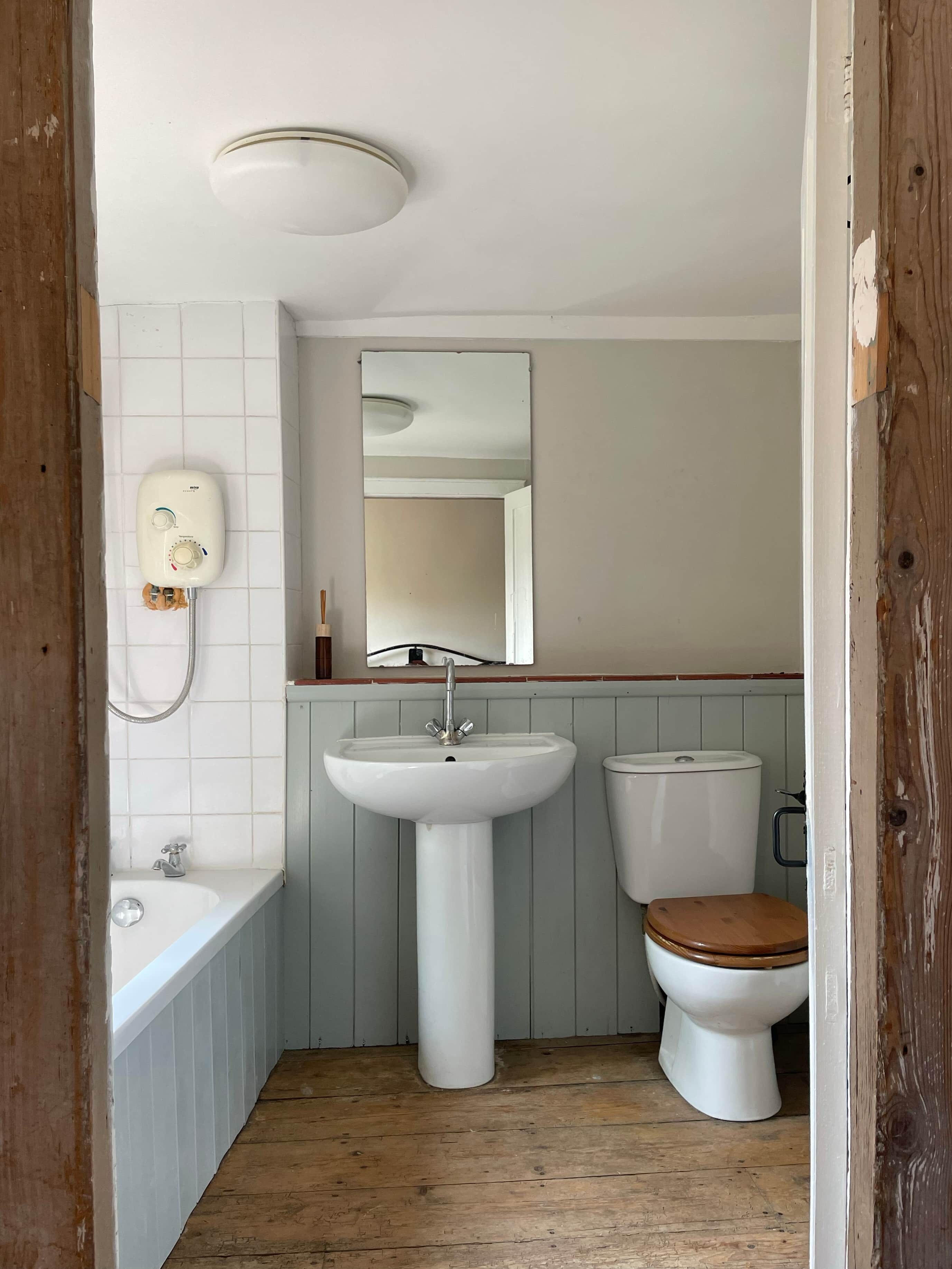 Een badkamer met een wastafel op een voetstuk, toilet en bad.