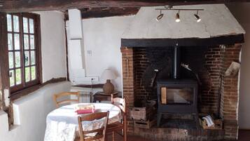 Une pièce rustique avec une cheminée en briques, une table avec des chaises et une fenêtre à carreaux.
