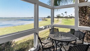 A covered outdoor seating area with a view of a golf course and water. - ⛱️Bay Views | Tram to Beach | Sandestin Resort | Pool | Vantage Pointe 43☀️ (Miramar Beach)
