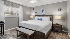 A bedroom with a bed, bedside lamps, a bench, a ceiling fan, and decorative wall art. - 🏖️Ground Floor 2BR | Pet Friendly | Pools + Golf Course | Seascape 91B🌞 (Miramar Beach)
