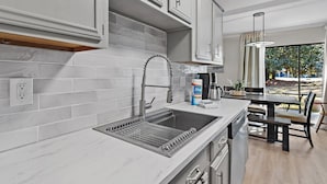 A modern kitchen with white cabinetry, a stainless steel sink, and a built-in oven. - 🏖️Ground Floor 2BR | Pet Friendly | Pools + Golf Course | Seascape 91B🌞 (Miramar Beach)