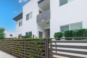 A modern building with a white facade, multiple windows, and a balcony. - Modern 3BR Getaway • 4 Beds +Free Parking Included (Hallandale Beach)