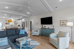 A modern living room with a sofa, armchairs, a coffee table, and a TV. - Backyard Pool Oasis and Coastal Charm in OKI (Oak Island)