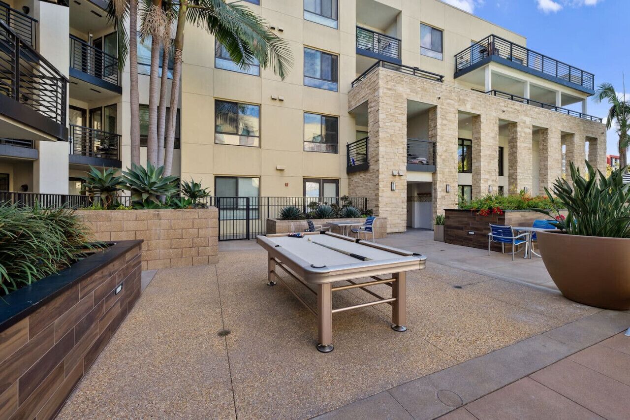 A pool table in an outdoor courtyard with a multi-story building in the background.