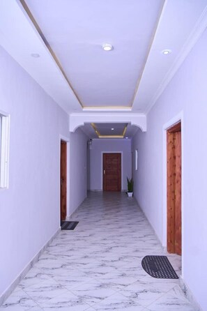A hallway with marble flooring, white walls, and wooden doors. - Discover modern comfort and style in this peaceful one-bedroom apartment. (Malindi)