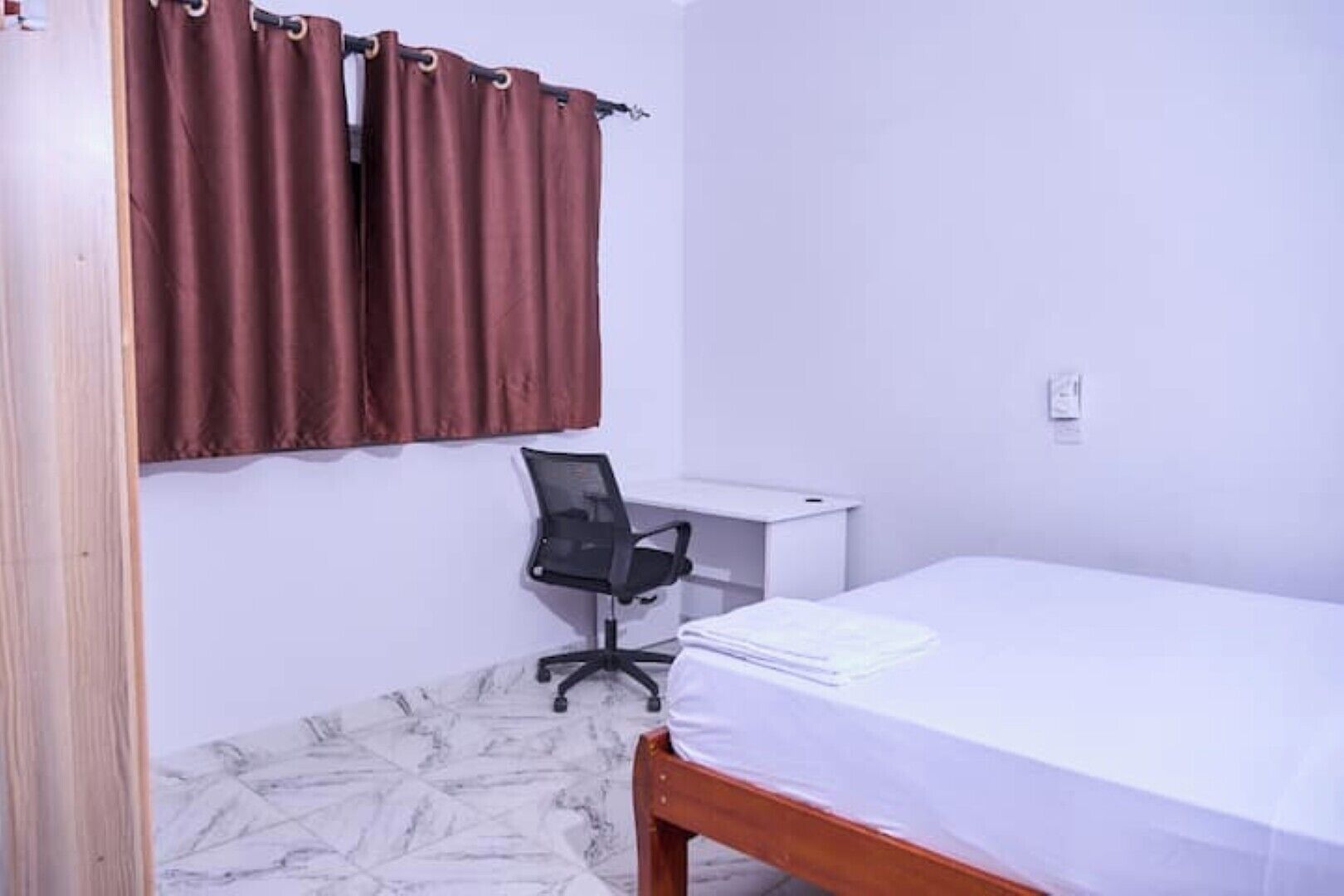 A bedroom with a bed, a desk, and a chair.