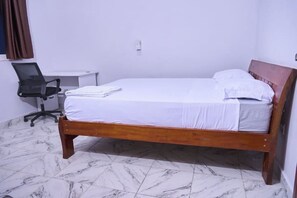 Un dormitorio con una cama de madera, un escritorio y una silla.
