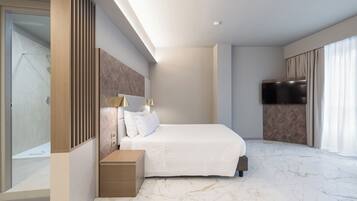 A modern hotel room with a large bed, a bedside table, a TV, and a glass shower area.
