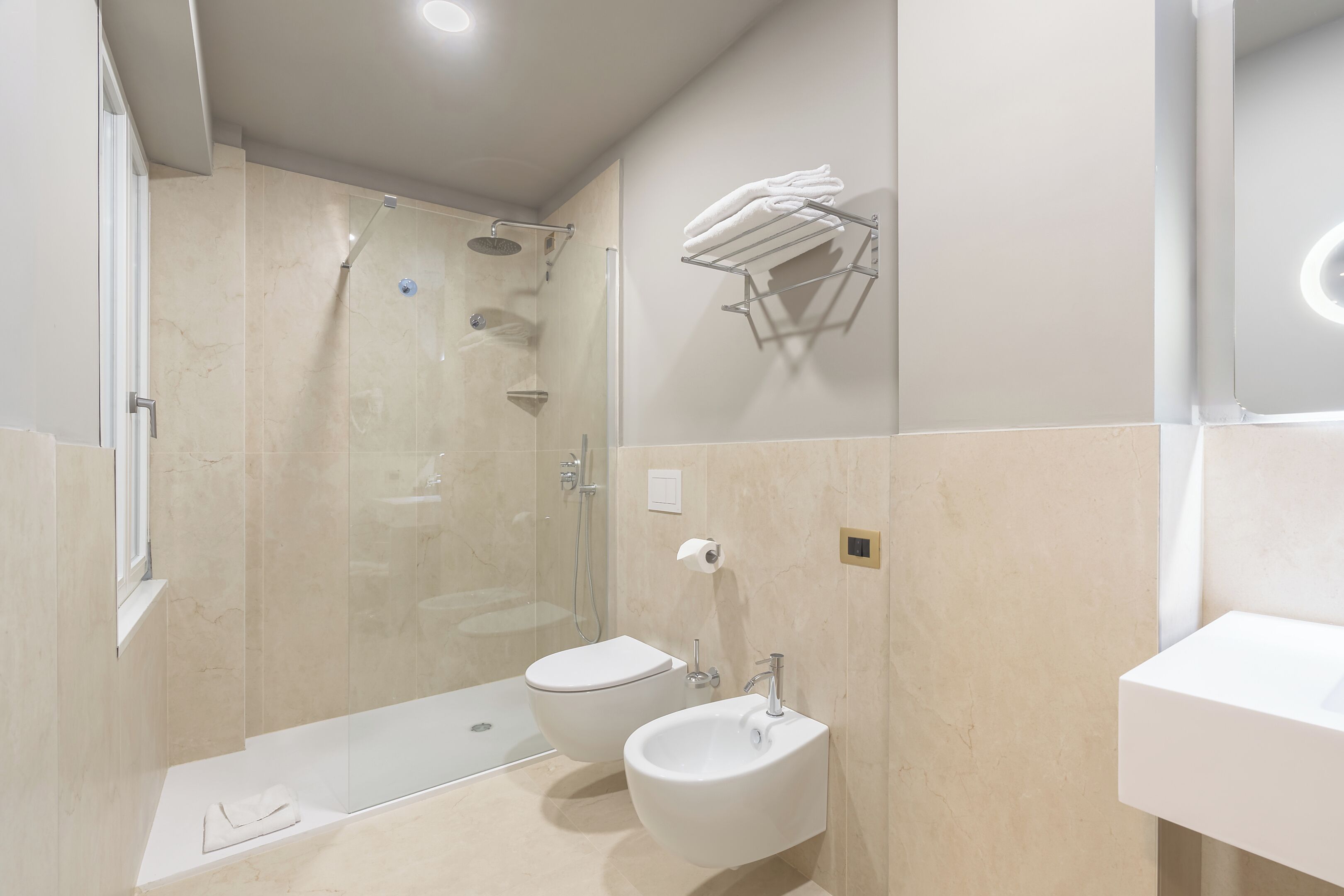 A modern bathroom with a glass-enclosed shower, a toilet, and a sink.