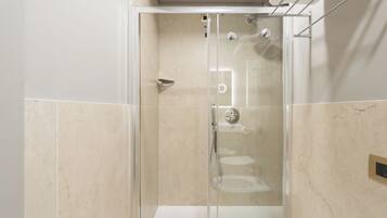 A modern bathroom with a glass-enclosed shower, a white sink, and a marble-tiled wall.