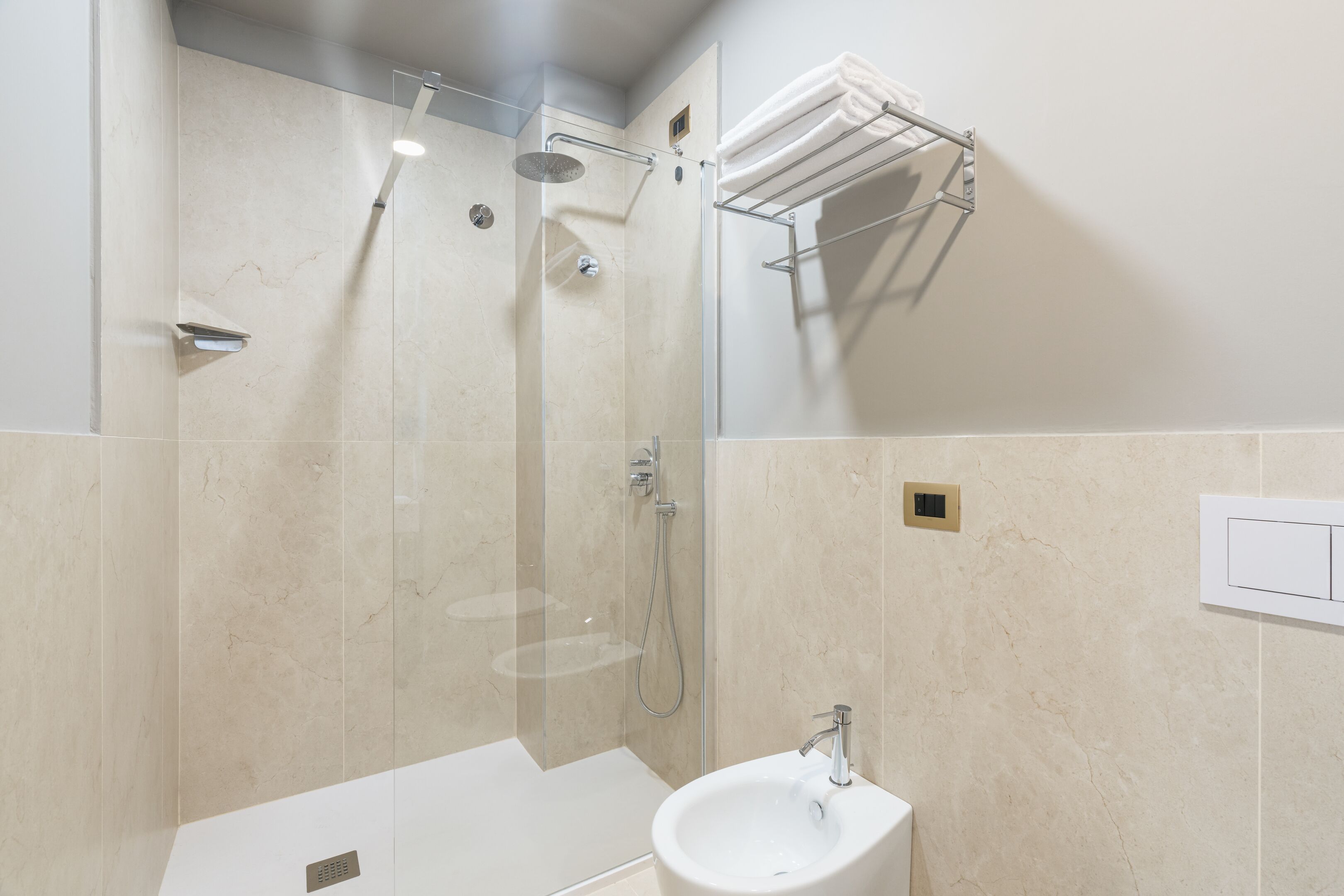A modern bathroom with a glass-enclosed shower, a white sink, and a towel rack.