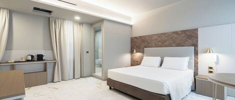 A modern hotel room with a large bed, a desk, and a mirror.