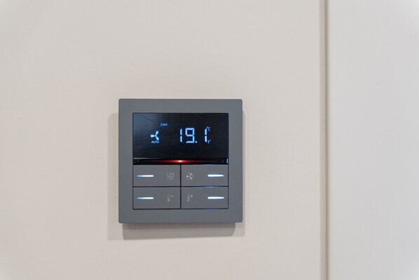 A digital thermostat with a display showing 19.1°C, set to 'COM' mode, and four control buttons below. - Baires Guest House (Milan)