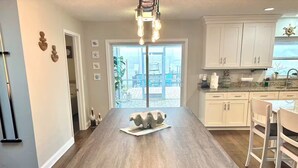Une cuisine moderne dotée d’un îlot central, de meubles blancs et offrant une vue sur l’extérieur.