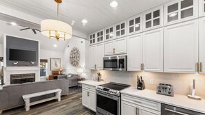 A modern kitchen with white cabinets, stainless steel appliances, and a built-in oven. - Steps from the sand! 4BR/3BA private home w/ heated pool, 6 seater gas golf cart (Panama City Beach, FL)