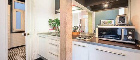 A compact kitchen with white cabinets, a black countertop, a built-in microwave, and a toaster.