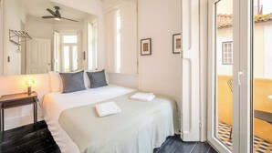 Et soveværelse med seng, sengebord, lampe og udsigt til balkonen.