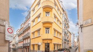 En gul bygning med en buet facade, en bil parkeret foran og et skilt med 'zona', der angiver en parkeringsfri zone.