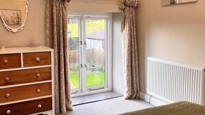 Een slaapkamer met een schuifdeur naar een achtertuin, een houten dressoir en een witte radiator.