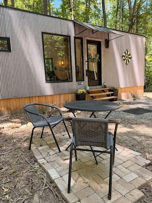 A modern cabin with a dining area featuring two chairs and a table, a wooden bench, and a door with a window.