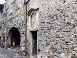 Ein Steinhaus mit einem schmalen Gang und einem Bogenportal.